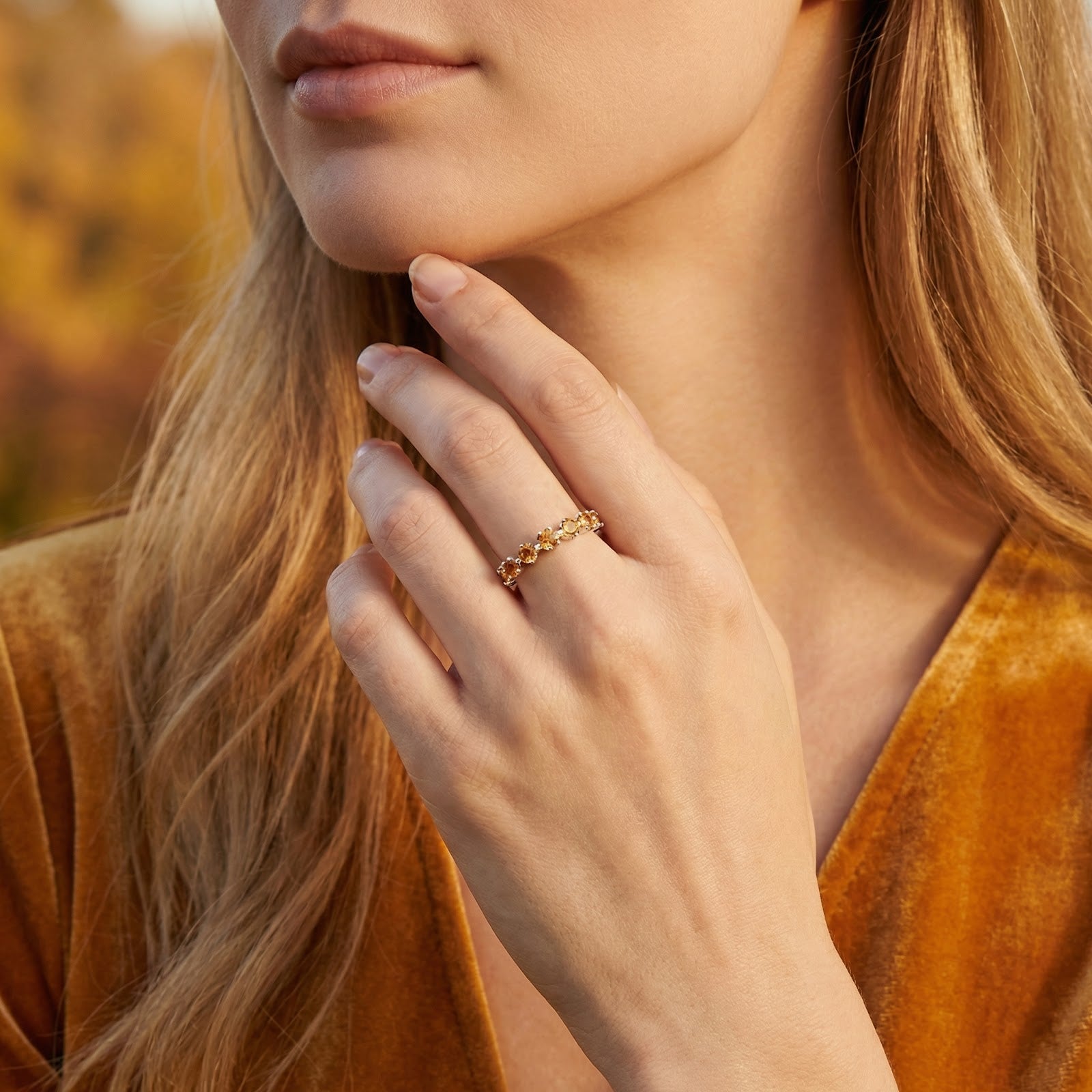 Model wearing the Novara sterling silver ring with honeyed simulated topaz stones against an autumn background.