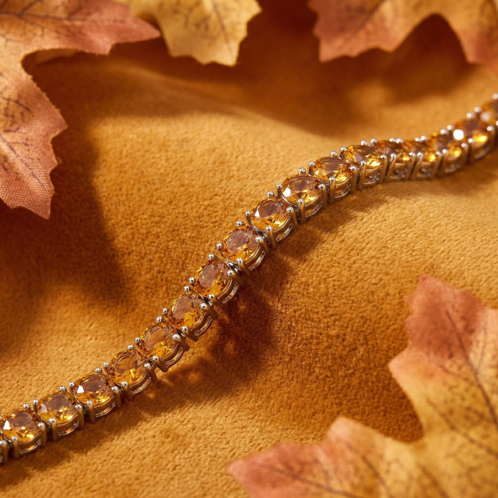 Macro shot of round-cut simulated honey topaz stones in a stainless steel tennis bracelet setting.