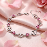 S925 sterling silver heart bracelet with cushion-cut simulated pink tourmaline on pink silk with rose petals.