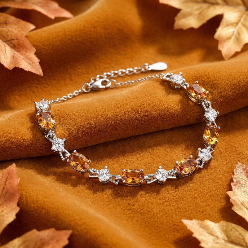 Honeyed topaz and sterling silver bracelet displayed on draped orange fabric with scattered autumn leaves.