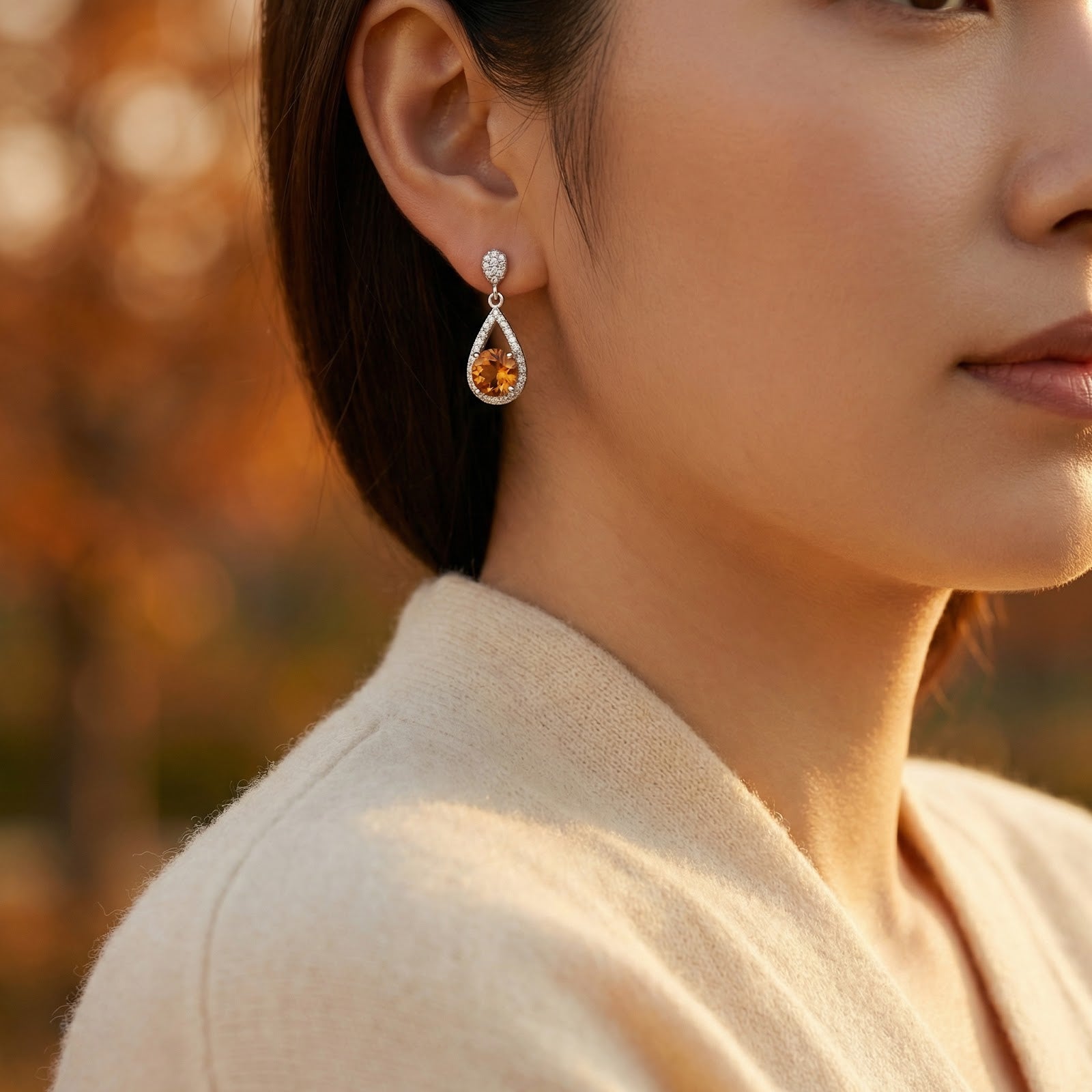 Woman wearing a S925 sterling silver pear drop earring with a round-cut simulated topaz birthstone.
