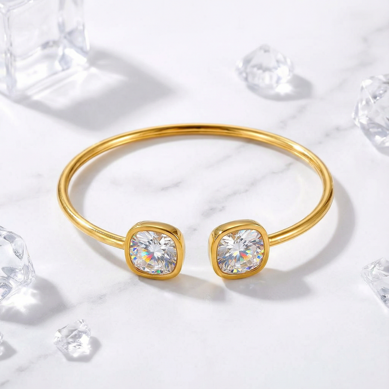 Gold-tone stainless steel Elaraea cuff featuring two cushion-cut moissanite stones on a marble background.