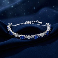 Angled view of the S925 sterling silver bracelet with oval-cut blue simulated sapphires on blue velvet.
