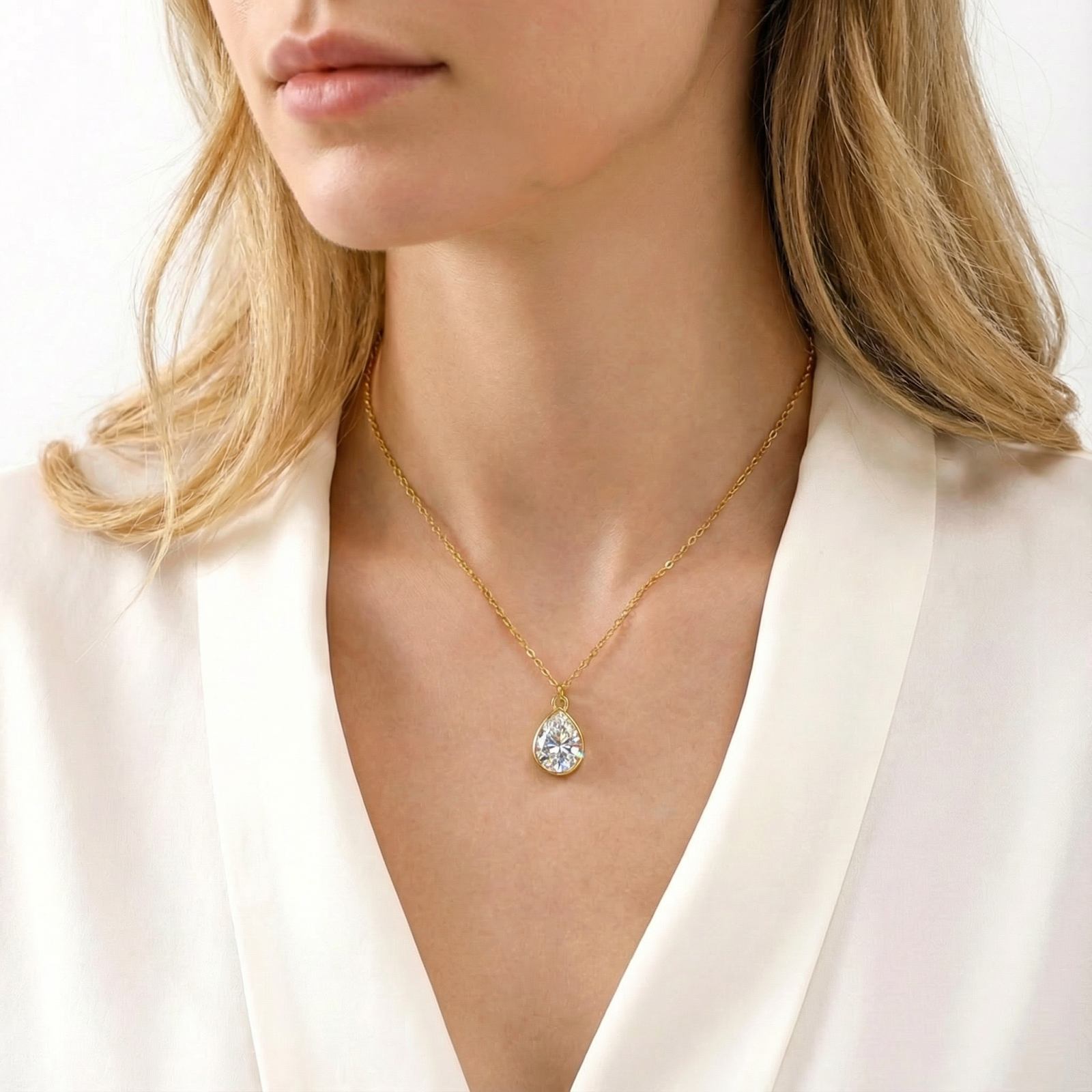 Woman wearing the gold-finished stainless steel Kyrielle Pear necklace with a brilliant pear-cut zirconia pendant.