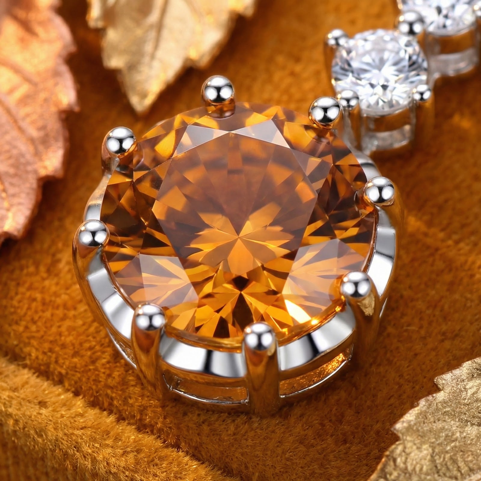 Macro detail of a round-cut honeyed topaz stone in a multi-prong sterling silver pendant setting.