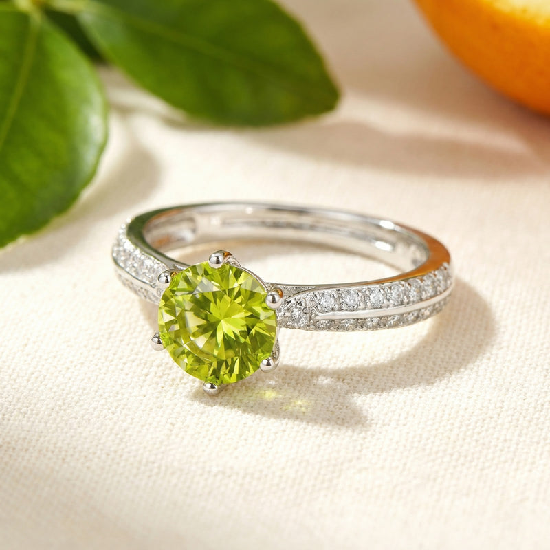 Close-up of a round-cut simulated peridot sterling silver ring with intricate milgrain and side stone accents.