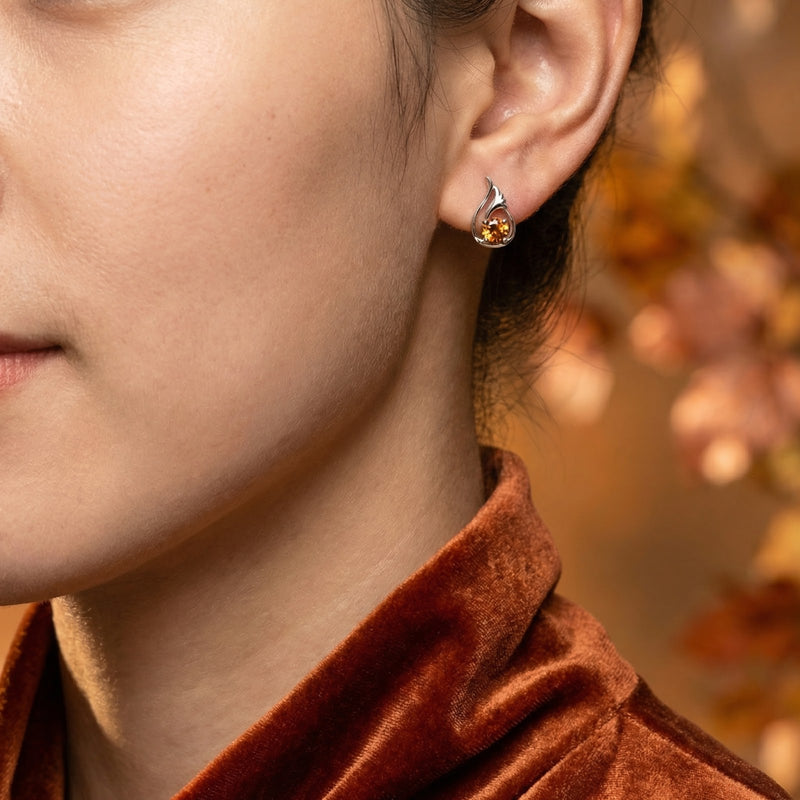 Close-up of a woman wearing a Melisara Bud sterling silver earring with a round-cut simulated topaz stone.