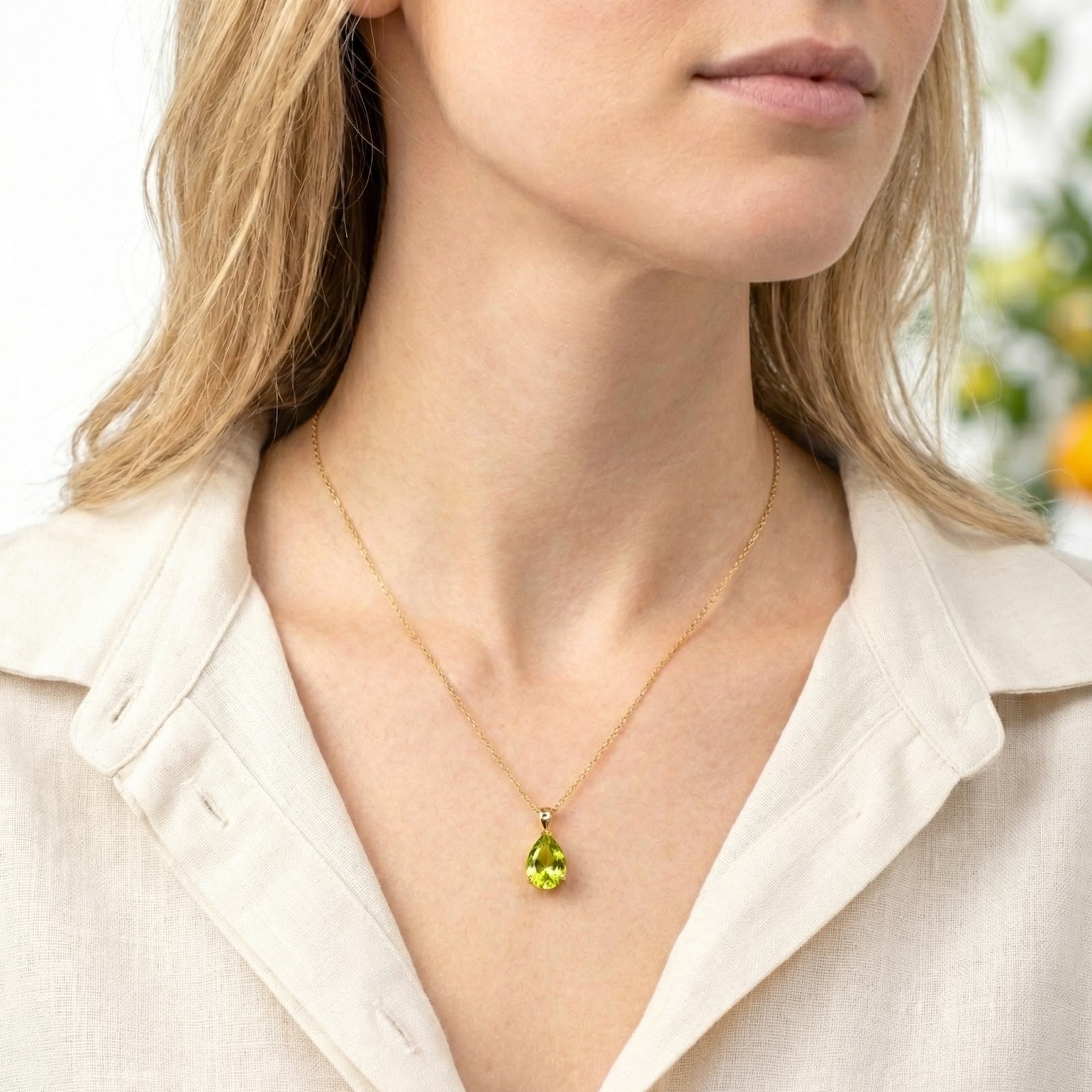 Model wearing the teardrop simulated peridot necklace in 18K gold vermeil with a white linen shirt.