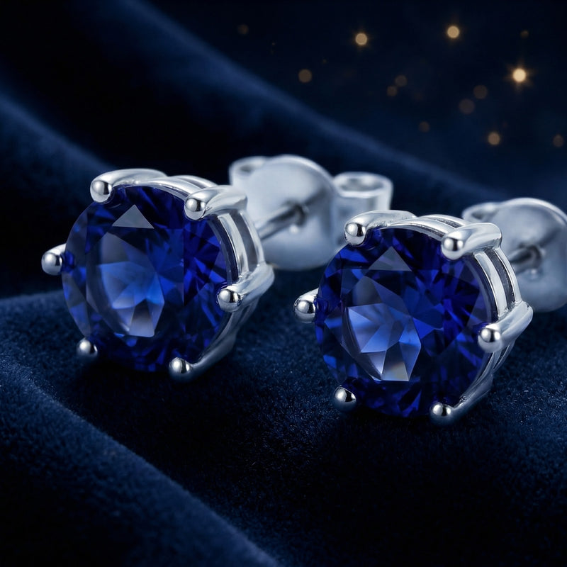 Macro view of round cut royal blue simulated sapphire studs with sterling silver prong settings.