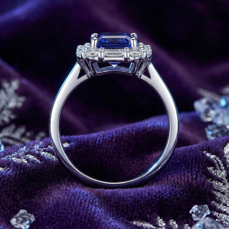 Side profile of the Elisande emerald cut simulated tanzanite sterling silver ring on purple velvet.