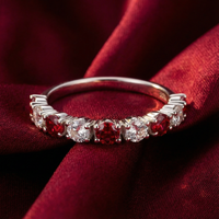 Rubielle S925 sterling silver half-eternity ring with round-cut red and clear stones resting on red silk fabric.