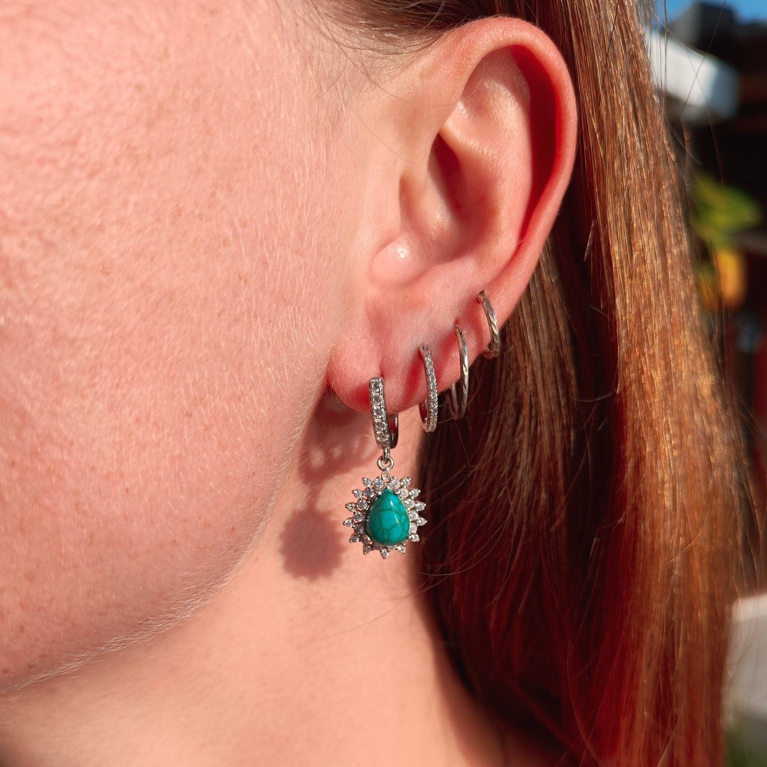 Blue Lagoon Turquoise Earrings featuring turquoise stones set in S925 sterling silver on a model in natural sunlight from the left ear