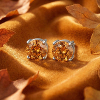 Round cut simulated topaz stud earrings in solid gold basket settings on golden velvet with autumn leaves.
