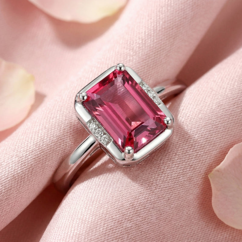 Macro view of an emerald-cut pink tourmaline ring in sterling silver showing detailed facets and side stones.