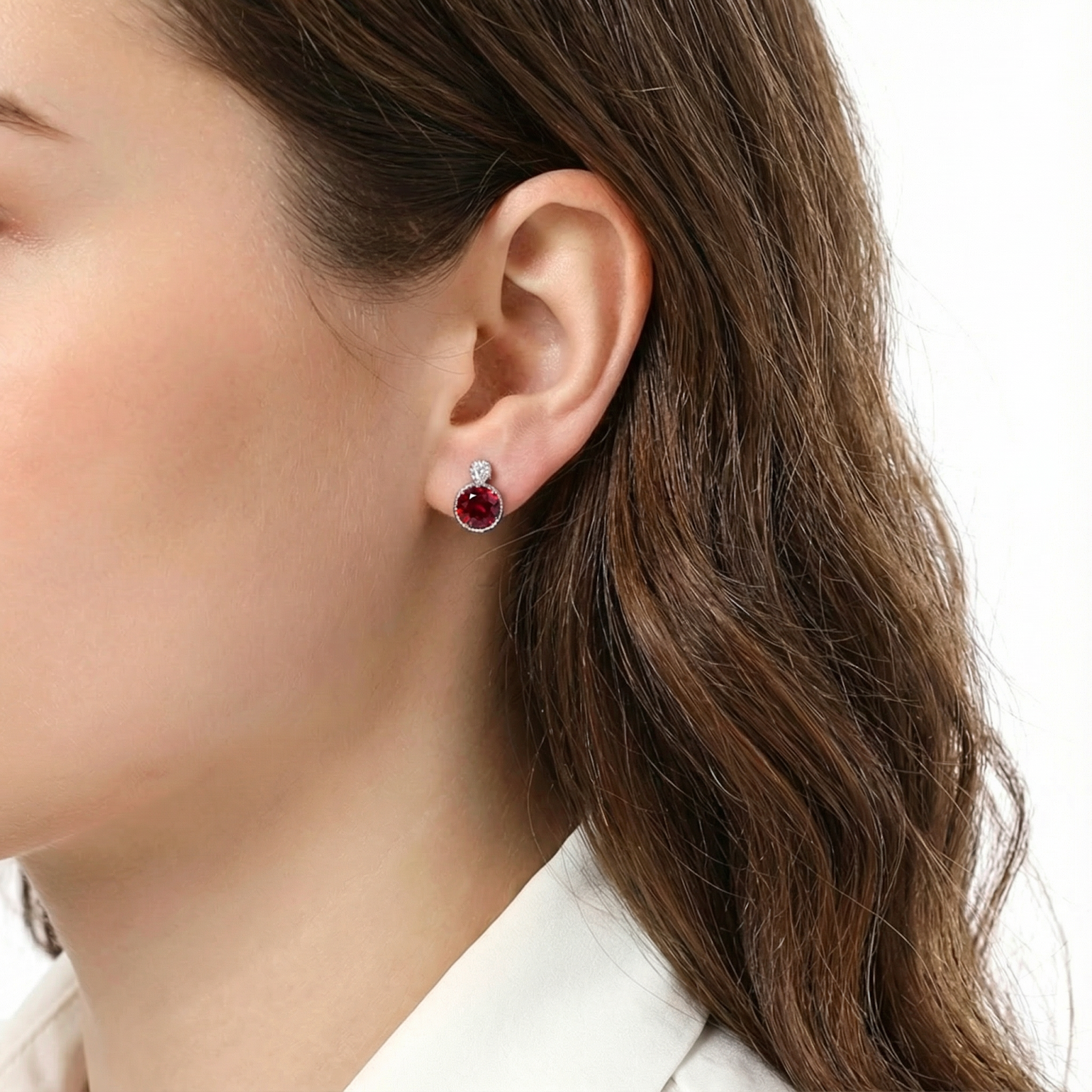 Round cut simulated ruby stud earring in S925 sterling silver shown on a model's ear.