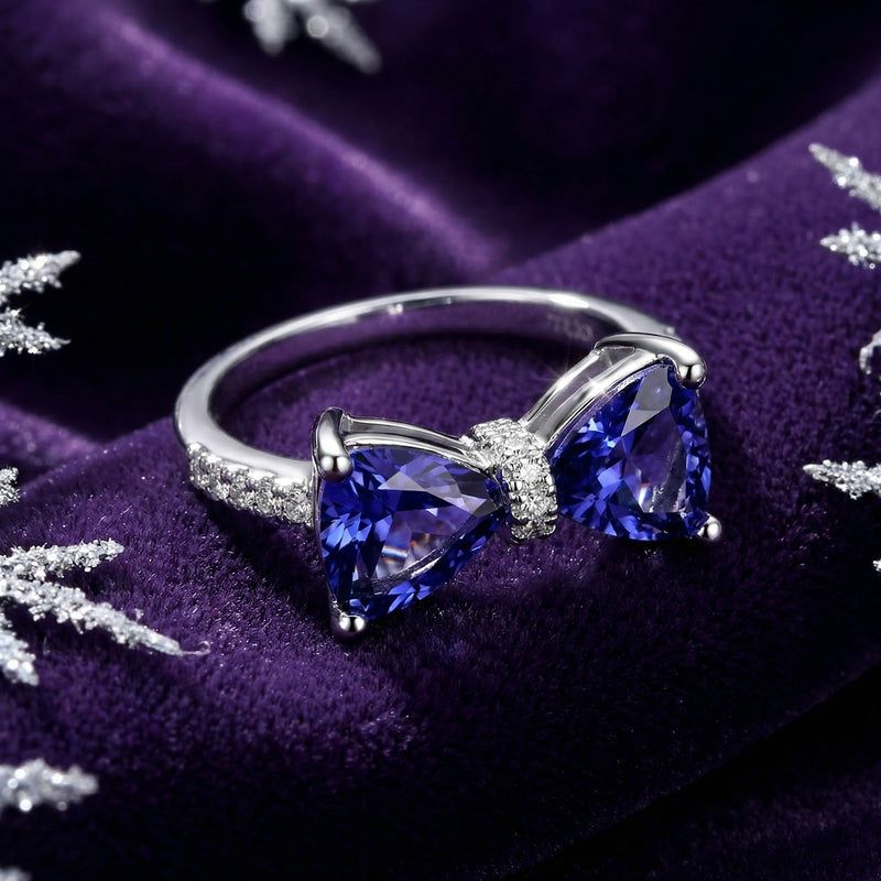 Macro view of the Evelia bow ring's trillion-cut simulated tanzanite stones and sterling silver setting.