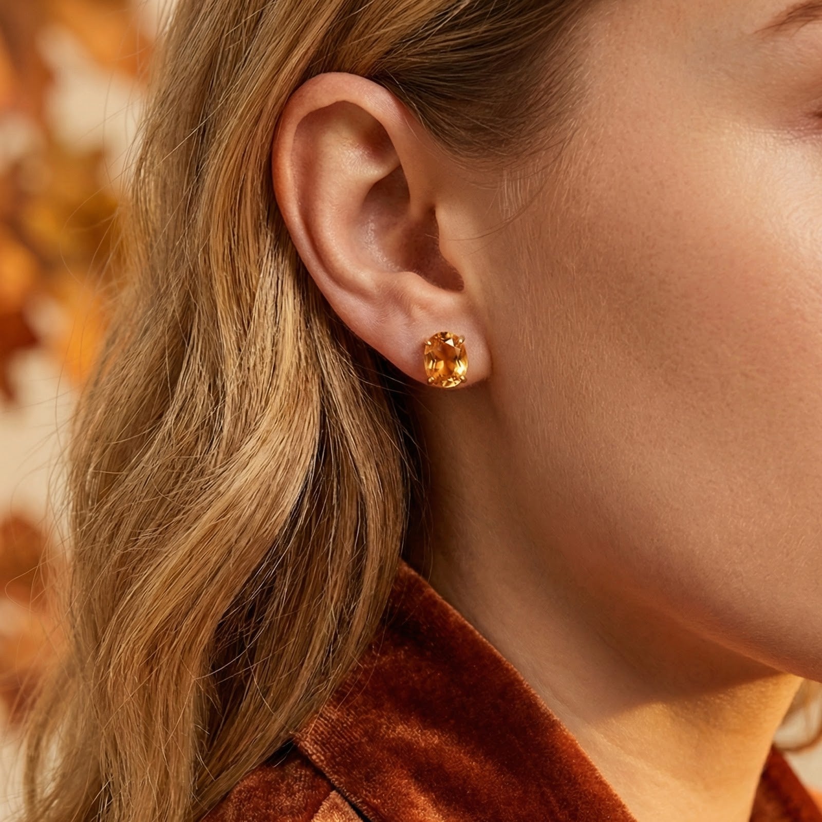 Close-up of a woman wearing the Amarantha 18K gold vermeil stud earring with a brilliant orange simulated topaz.