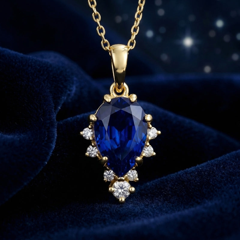 Detailed view of a pear-shaped royal blue sapphire pendant with accents on an 18K gold vermeil chain.