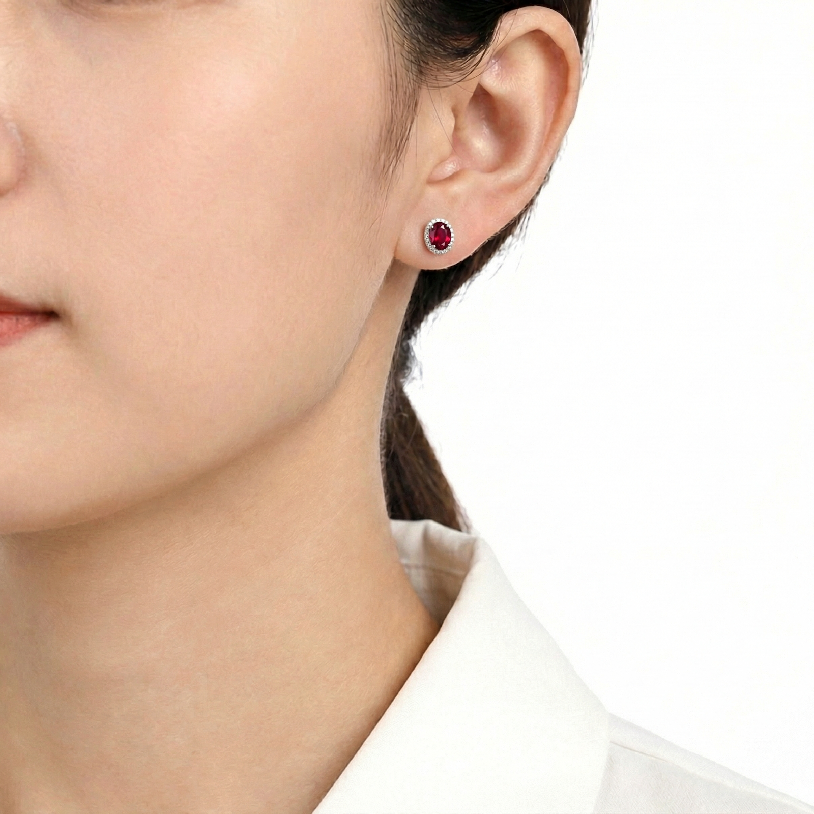 Woman wearing a Lysielle oval simulated ruby halo stud earring in S925 sterling silver.