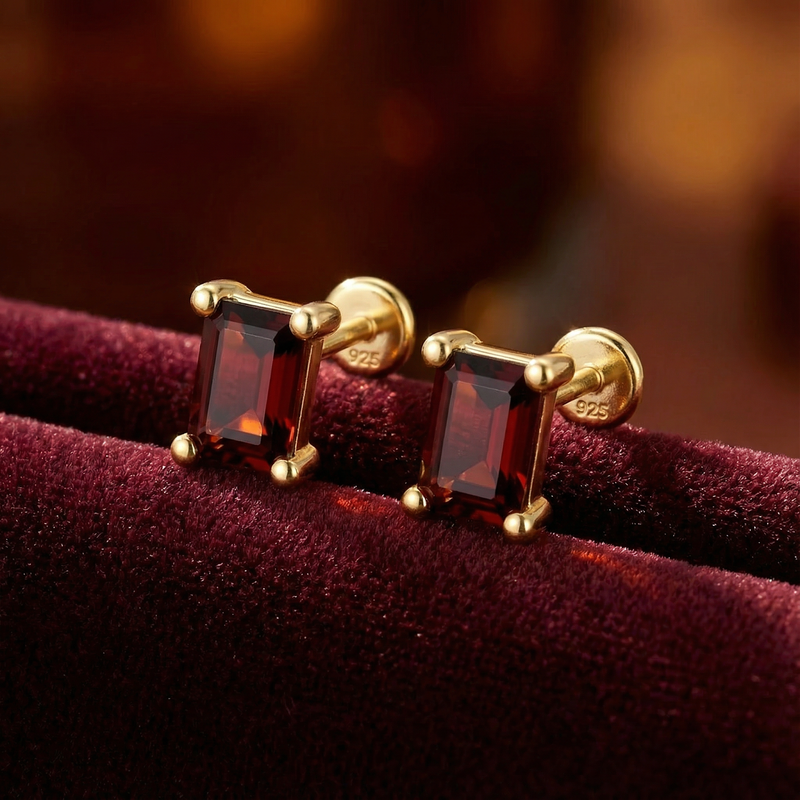 Close-up of baguette cut simulated garnet stud earrings in 18K gold vermeil showing the S925 sterling silver hallmark.