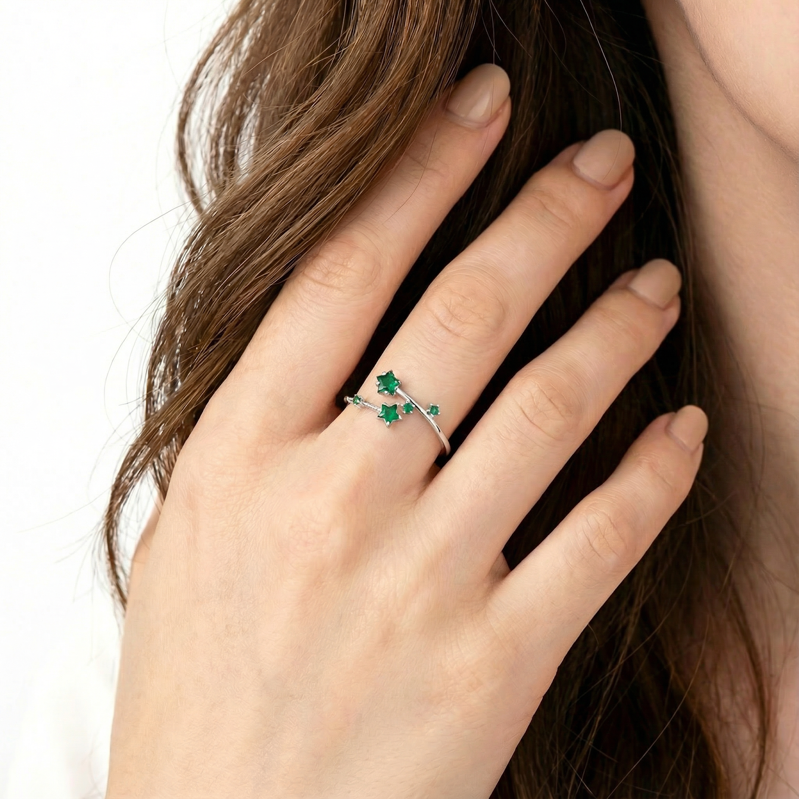 Woman wearing the silver Vega Star ring with green simulated emeralds on her ring finger.