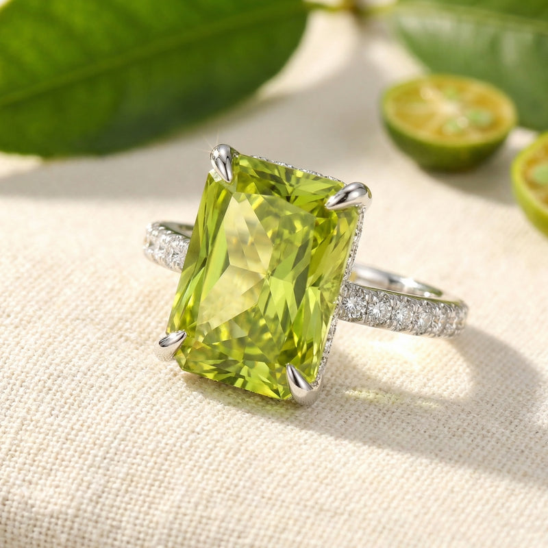 Macro view of a radiant-cut simulated peridot ring in silver, highlighting precision facets and pavé setting.