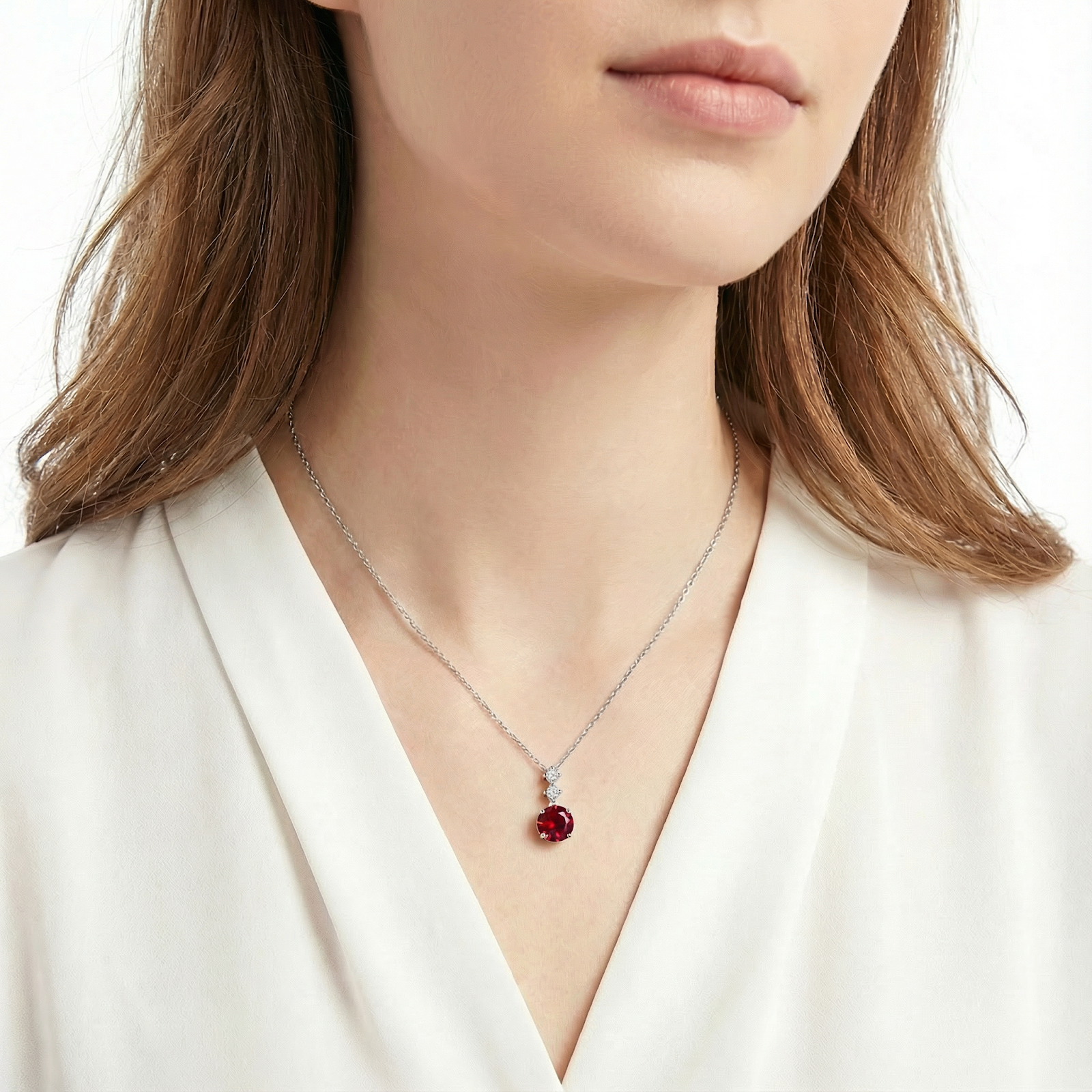 Model wearing the Lucerise Drop simulated ruby necklace in sterling silver against a white background.