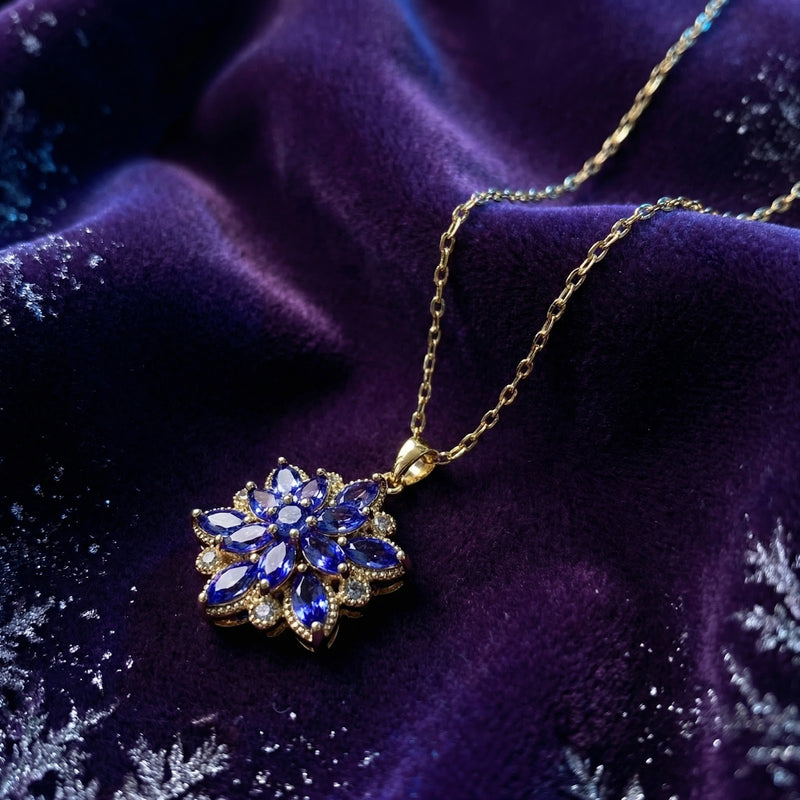 Close-up of the gold finish stainless steel tanzanite bloom necklace resting on purple velvet with snowflakes.