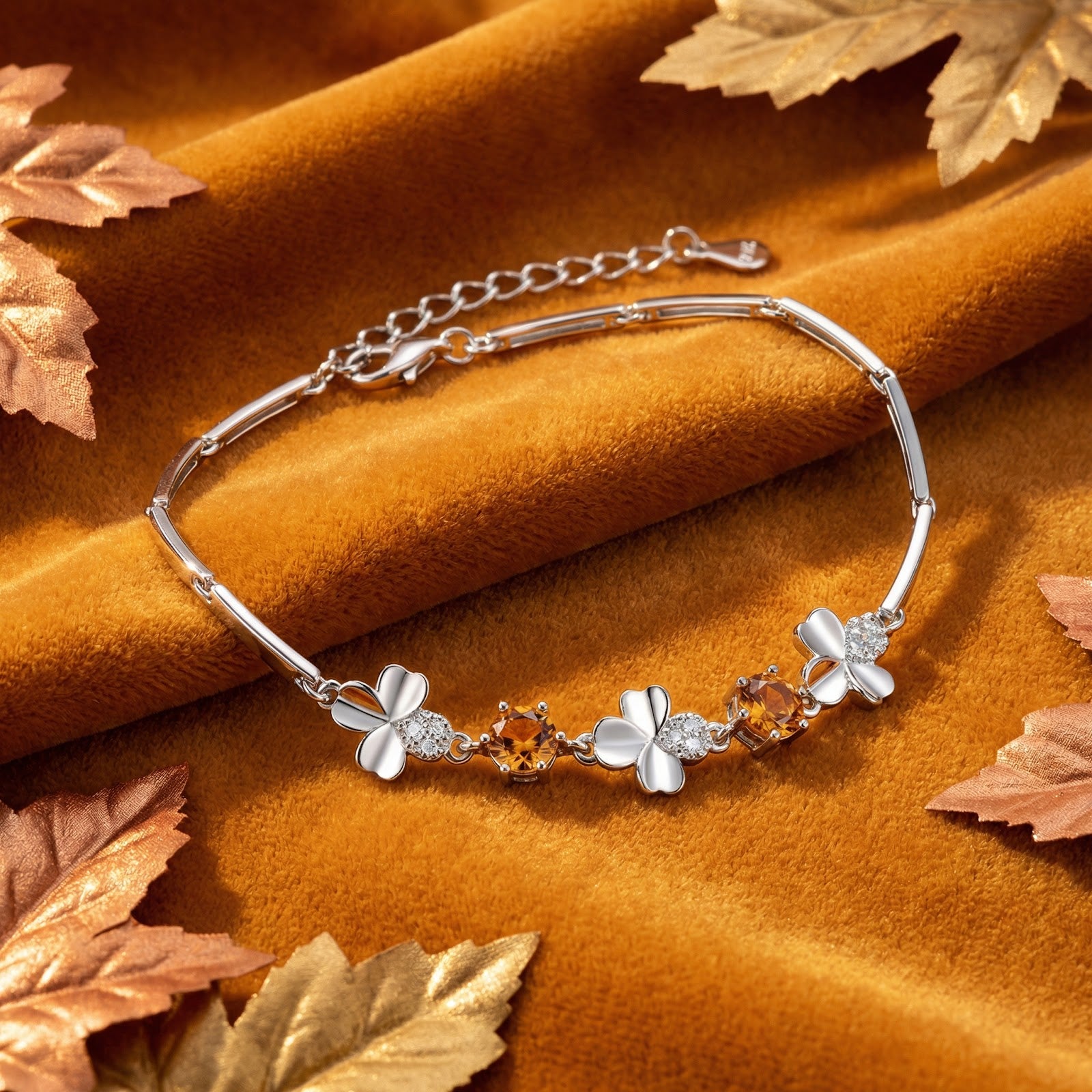 Sterling silver Zenielle clover bracelet with round honey simulated topaz on a brown velvet background with leaves.