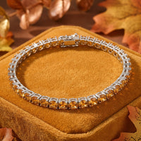 Stainless steel tennis bracelet with round simulated honey topaz November birthstones on an autumn background.