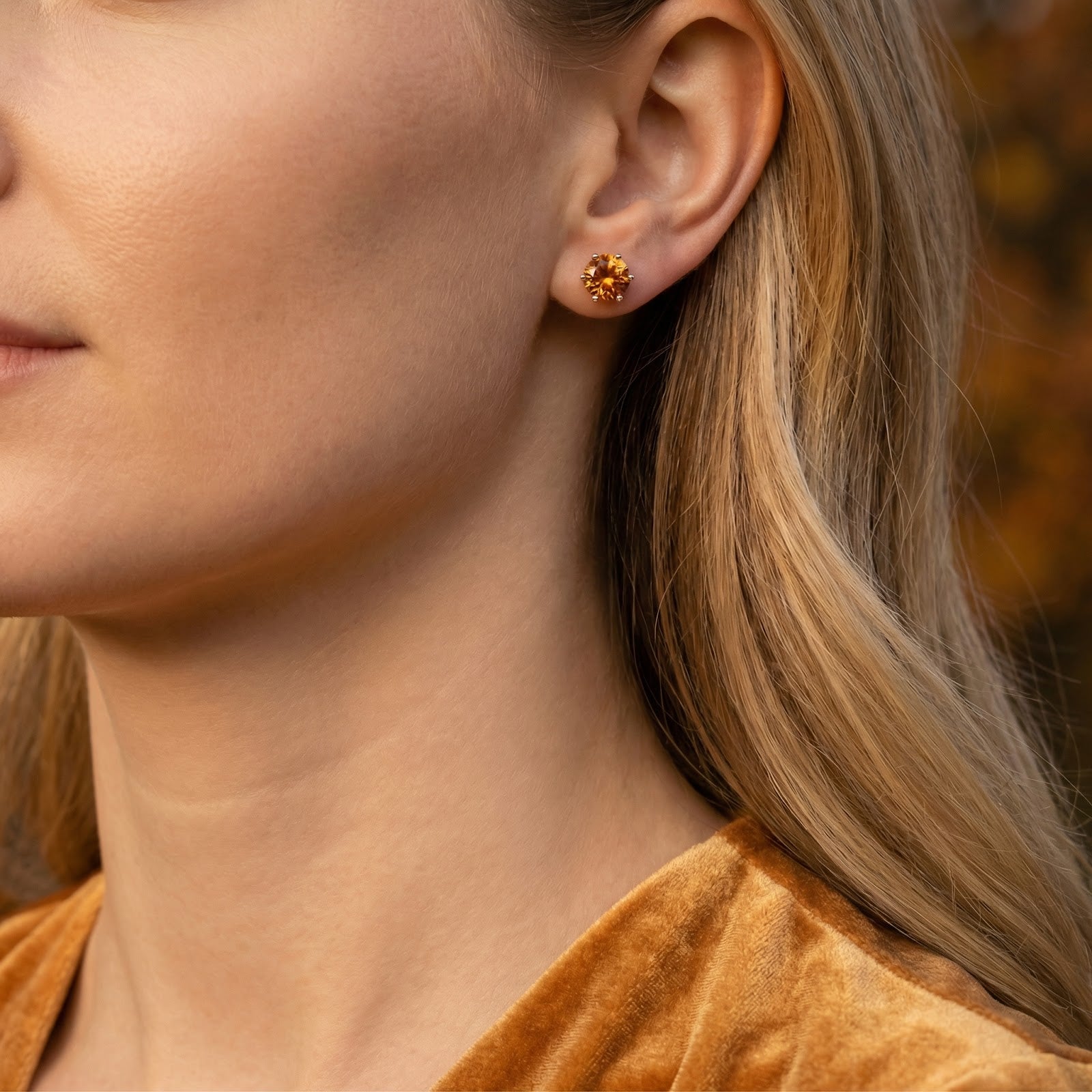 Round-cut simulated topaz stud earring in sterling silver shown on a model's ear.