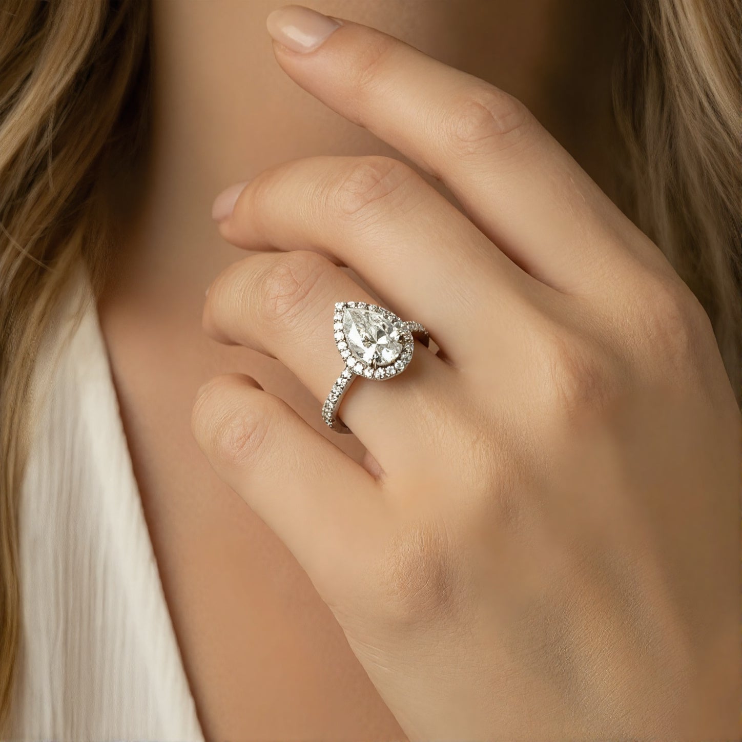 Close-up of a pear-cut simulated diamond halo ring in S925 sterling silver worn on a woman's hand.