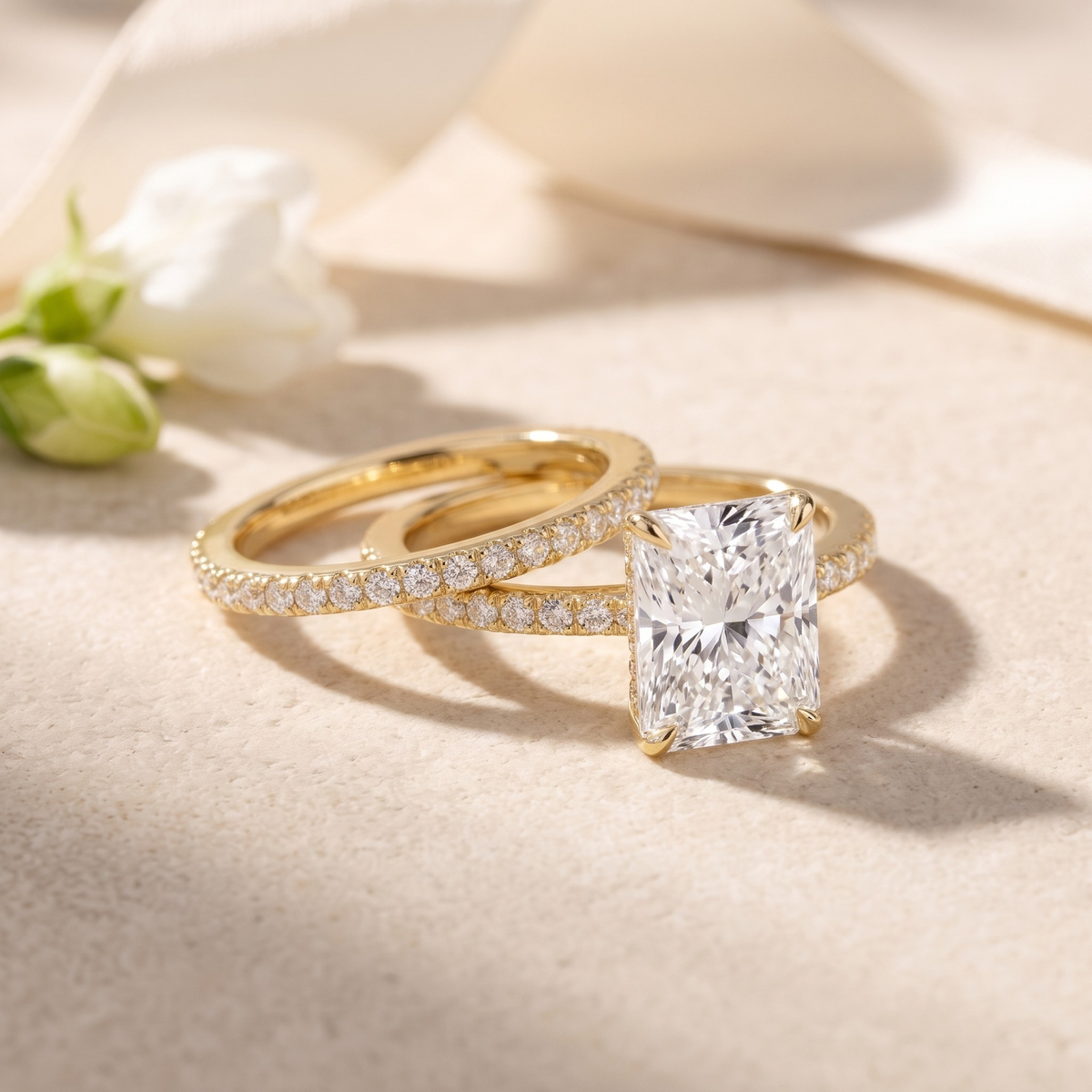 Two-piece radiant-cut moissanite ring set in yellow gold, angled closeup.