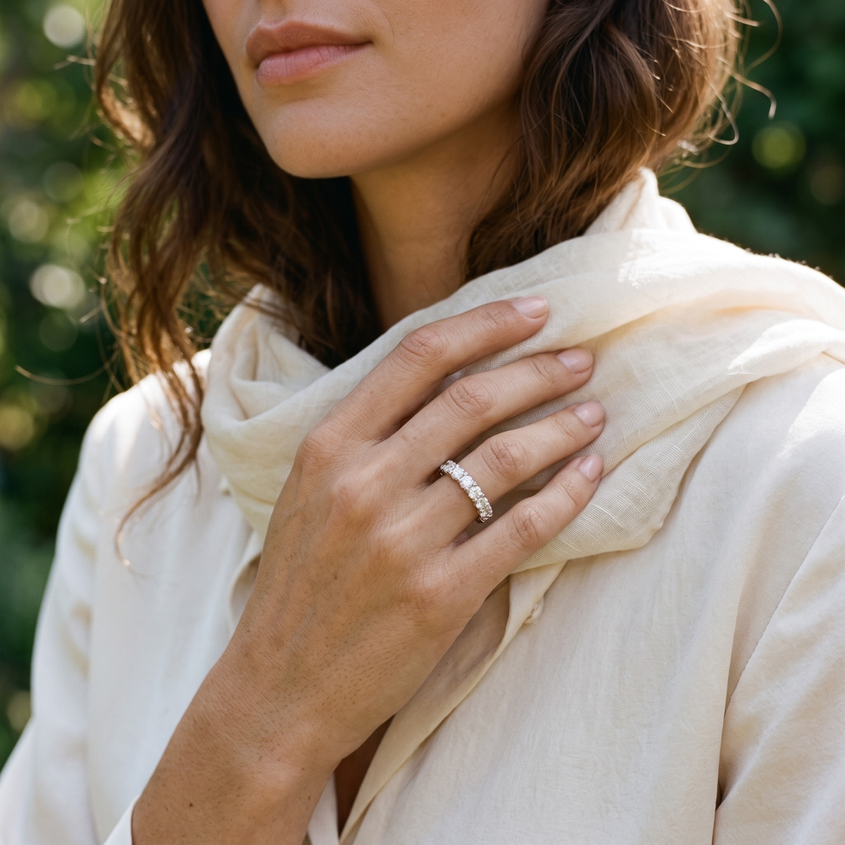 Silver moissanite eternity band worn on a model's hand near her scarf.