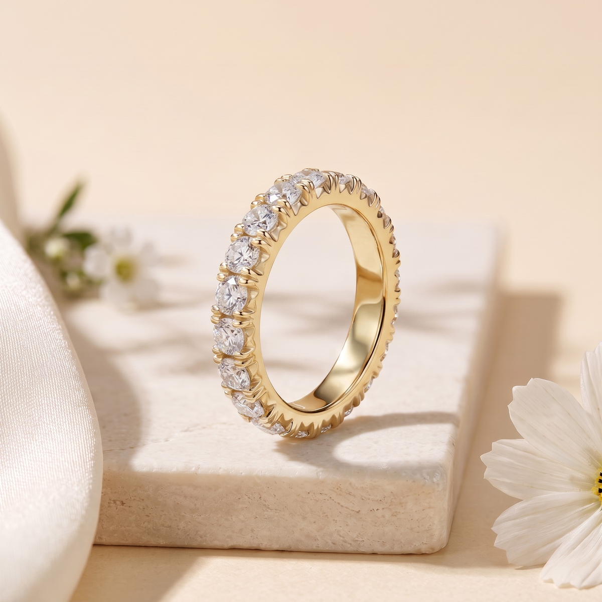 Round moissanite eternity band in yellow gold, upright product view.