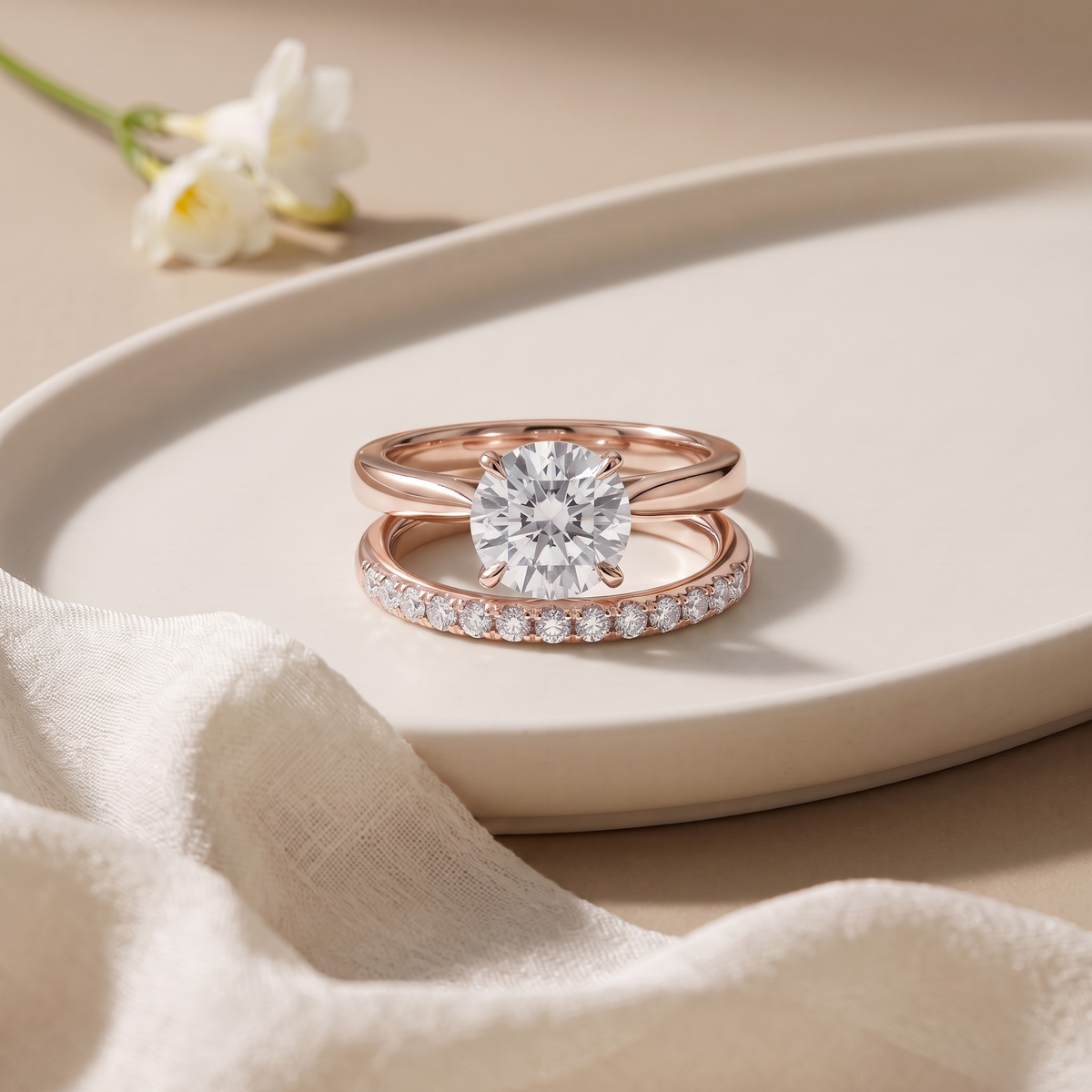 Round-cut moissanite solitaire and separate pavé band in rose gold, front product view.