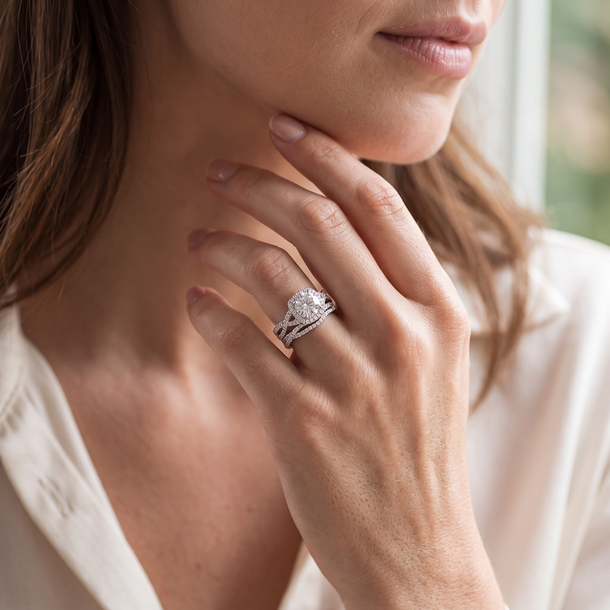 Silver round halo bridal ring set worn by a model, portrait detail