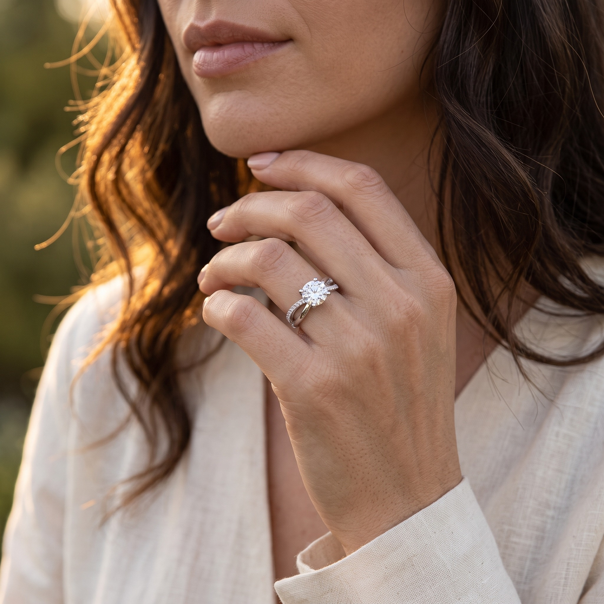 Silver twist pavé round moissanite ring worn on a model's hand near her chin.