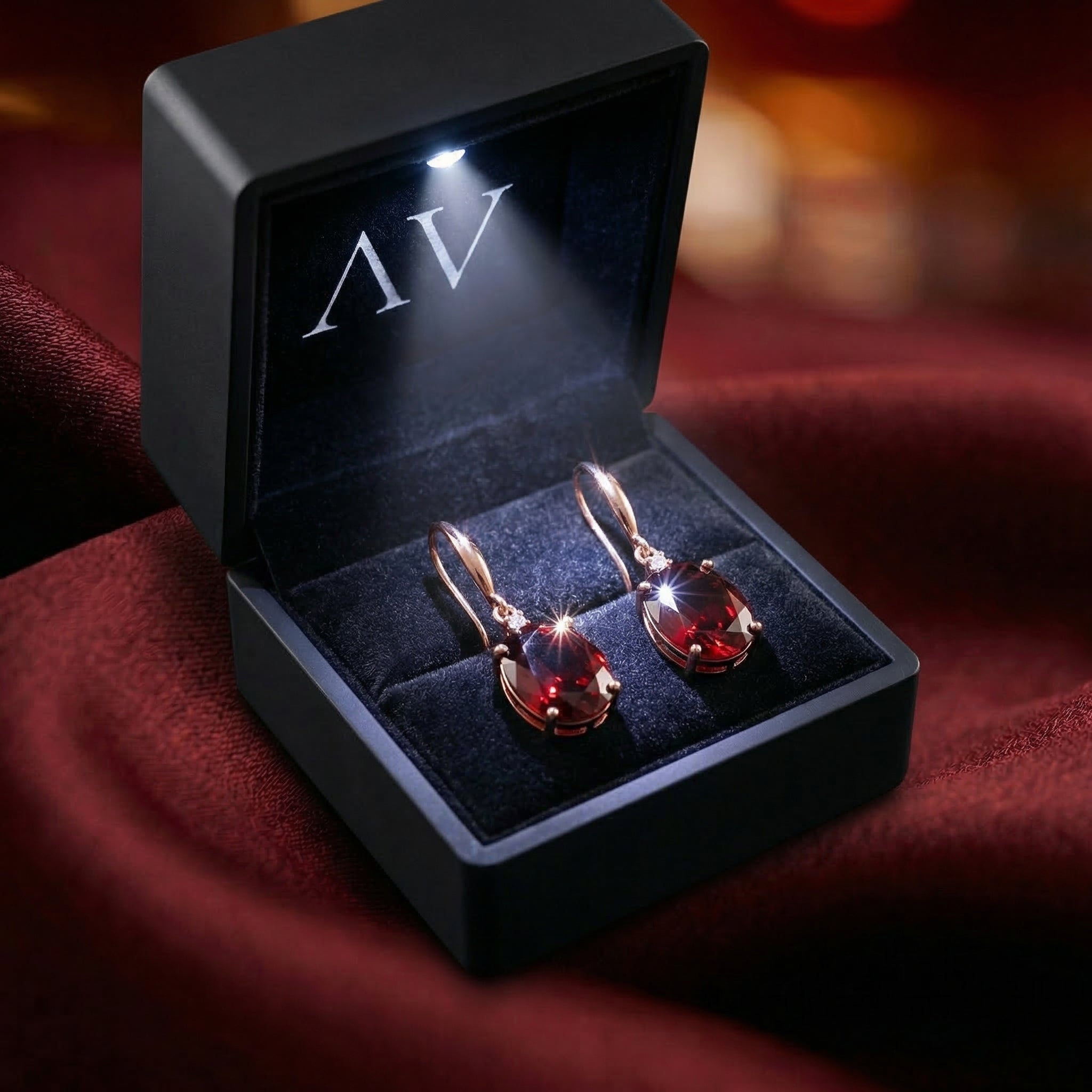 18K rose gold oval cut natural garnet drop earrings with diamond accents in a lighted luxury gift box.