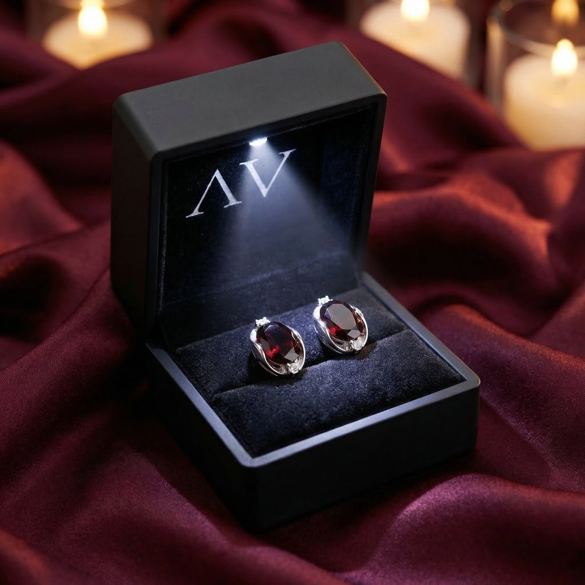 8x10mm oval cut garnet earrings in sterling silver inside a black LED-lighted jewelry presentation box.