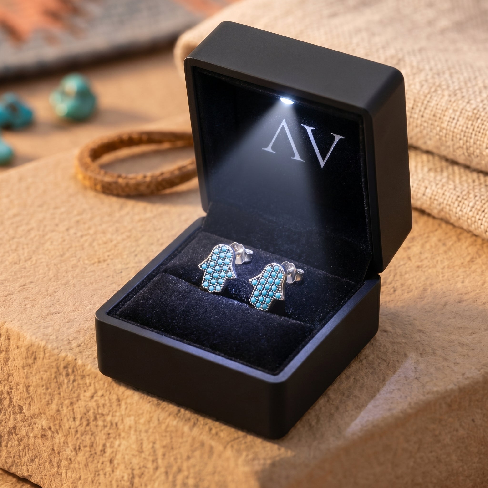 Silver Hamsa hand turquoise earrings displayed in a black lighted jewelry gift box.