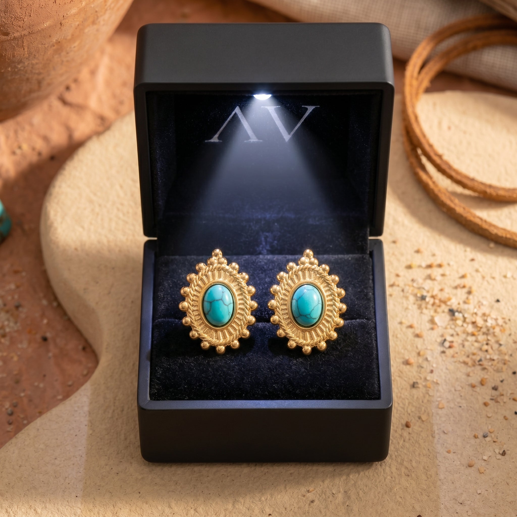 Gold-tone turquoise-hued drop earrings presented in a black lighted jewelry gift box.