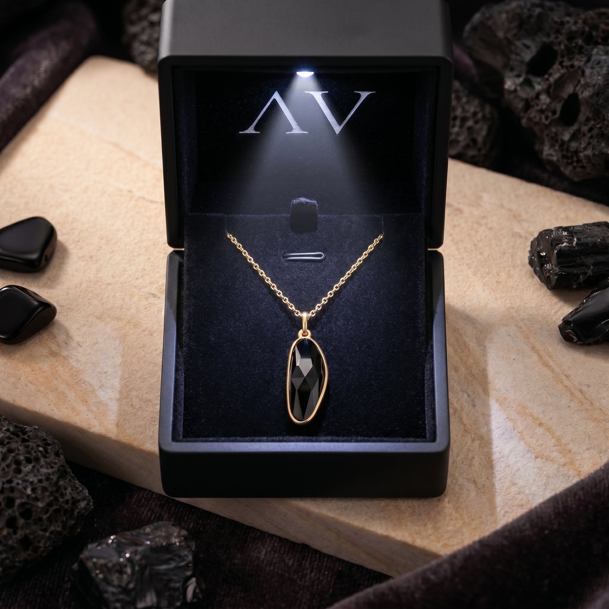 Gold black onyx pendant necklace displayed in a premium black lighted jewelry box with AV branding.