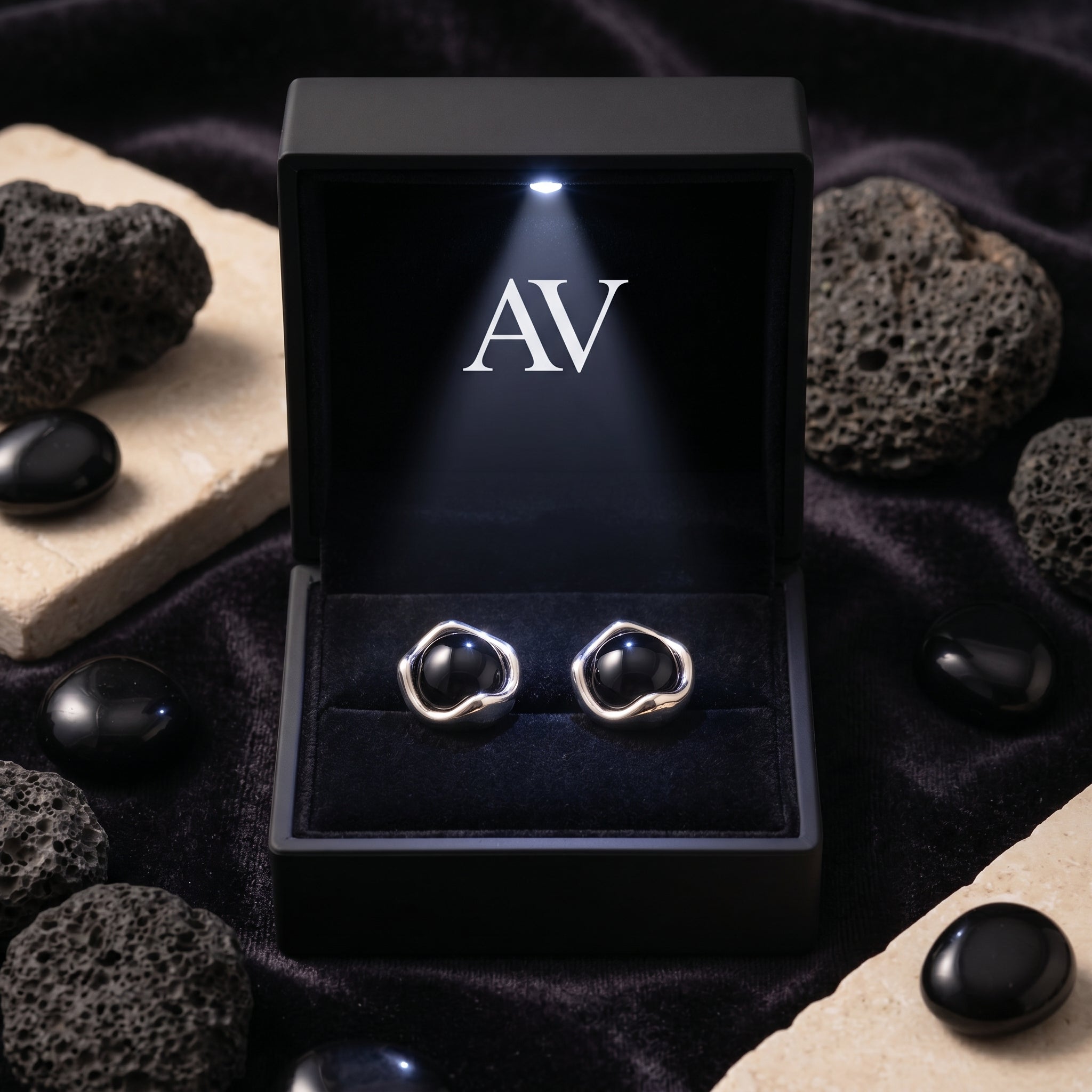 Round black onyx earrings in silver settings displayed inside a lighted black jewelry gift box.