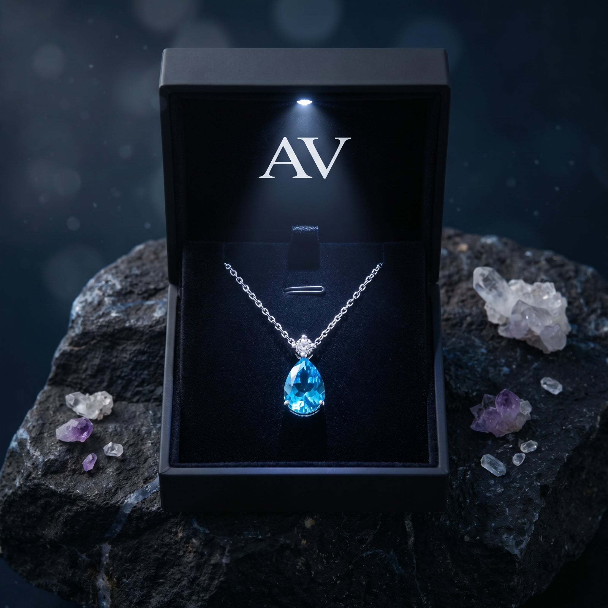 Pear cut Swiss Blue topaz necklace inside a black LED-lighted jewelry box, placed on a dark rock.