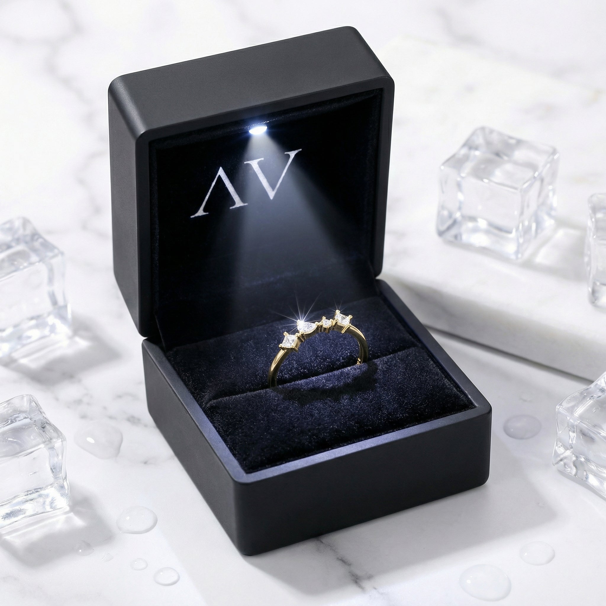 18K gold vermeil moissanite ring presented in a black LED-lit jewelry box on a marble and ice background.