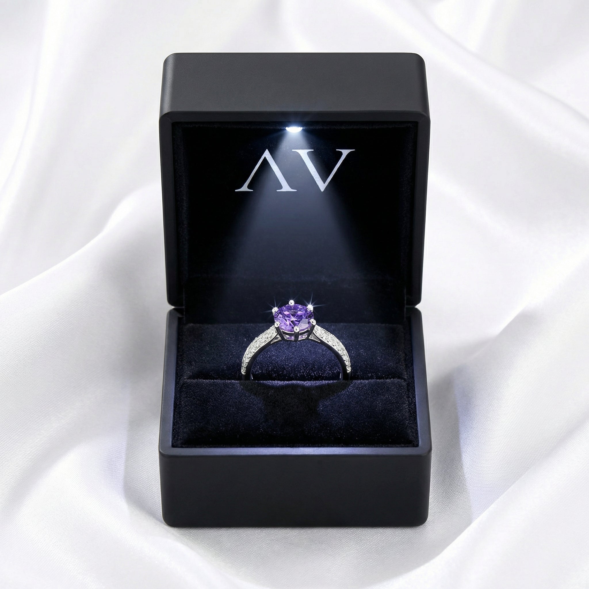 Round-cut simulated amethyst sterling silver ring inside a black LED-lighted presentation box on white silk.