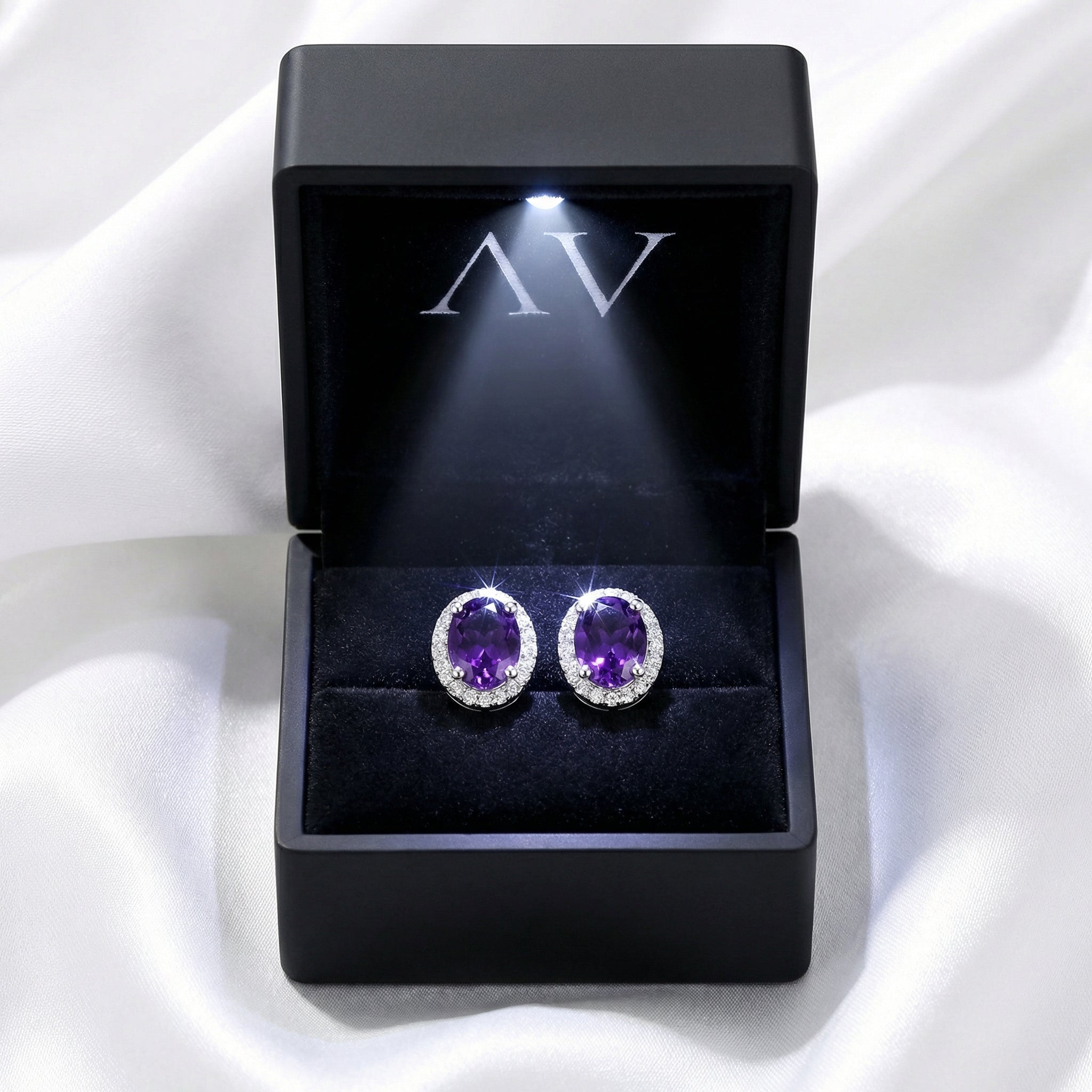 Oval simulated amethyst halo earrings displayed in a black LED-lit jewelry presentation box.