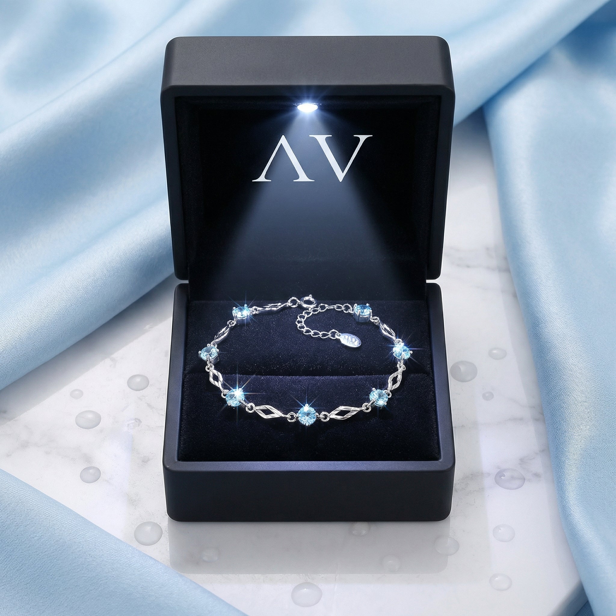 Etherea station bracelet in S925 sterling silver with simulated aquamarine in a lighted black gift box.