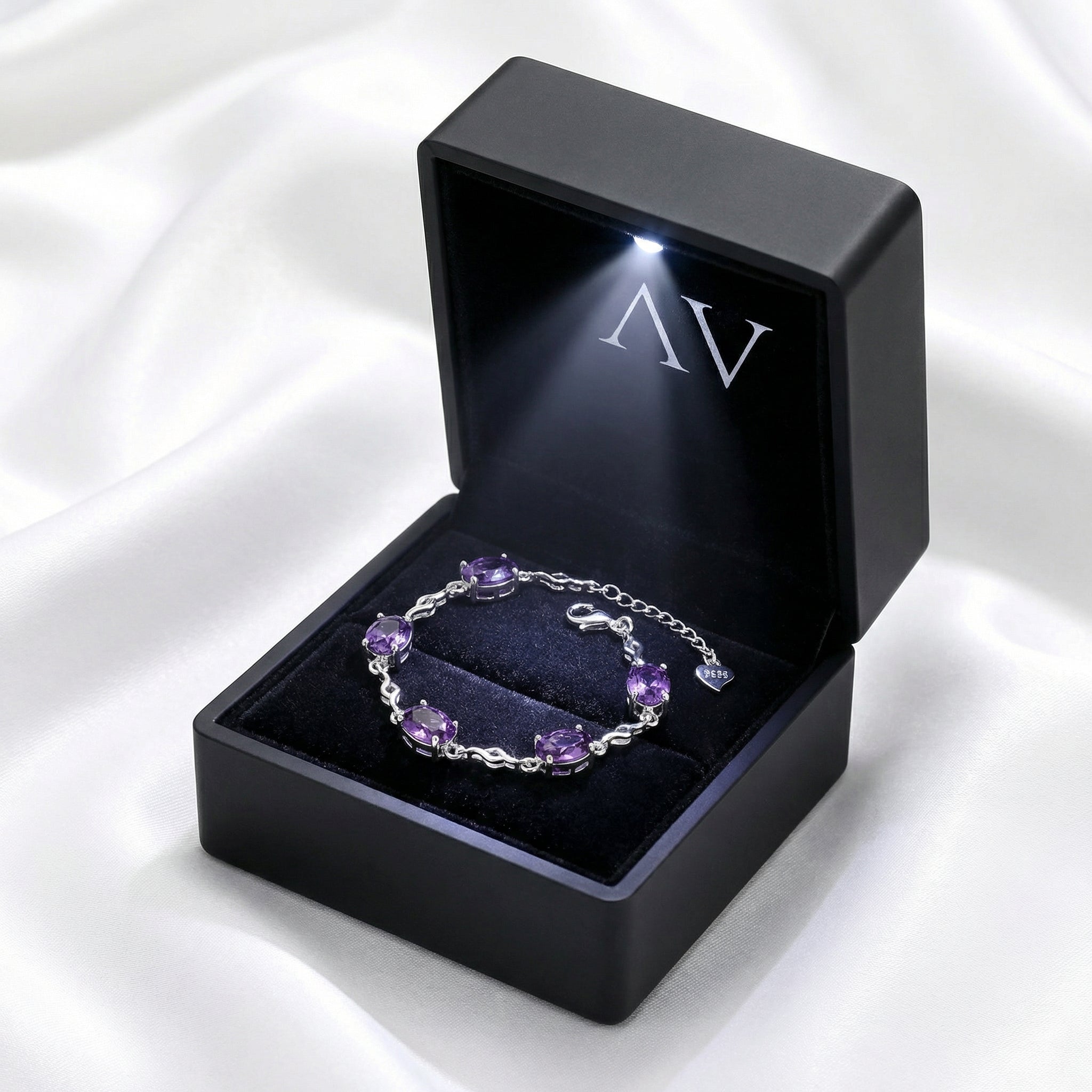 Simulated amethyst sterling silver station bracelet presented in a black LED-lighted jewelry gift box.